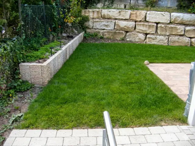 Gartengestaltung mit Rasenfläche und Natursteinmauer